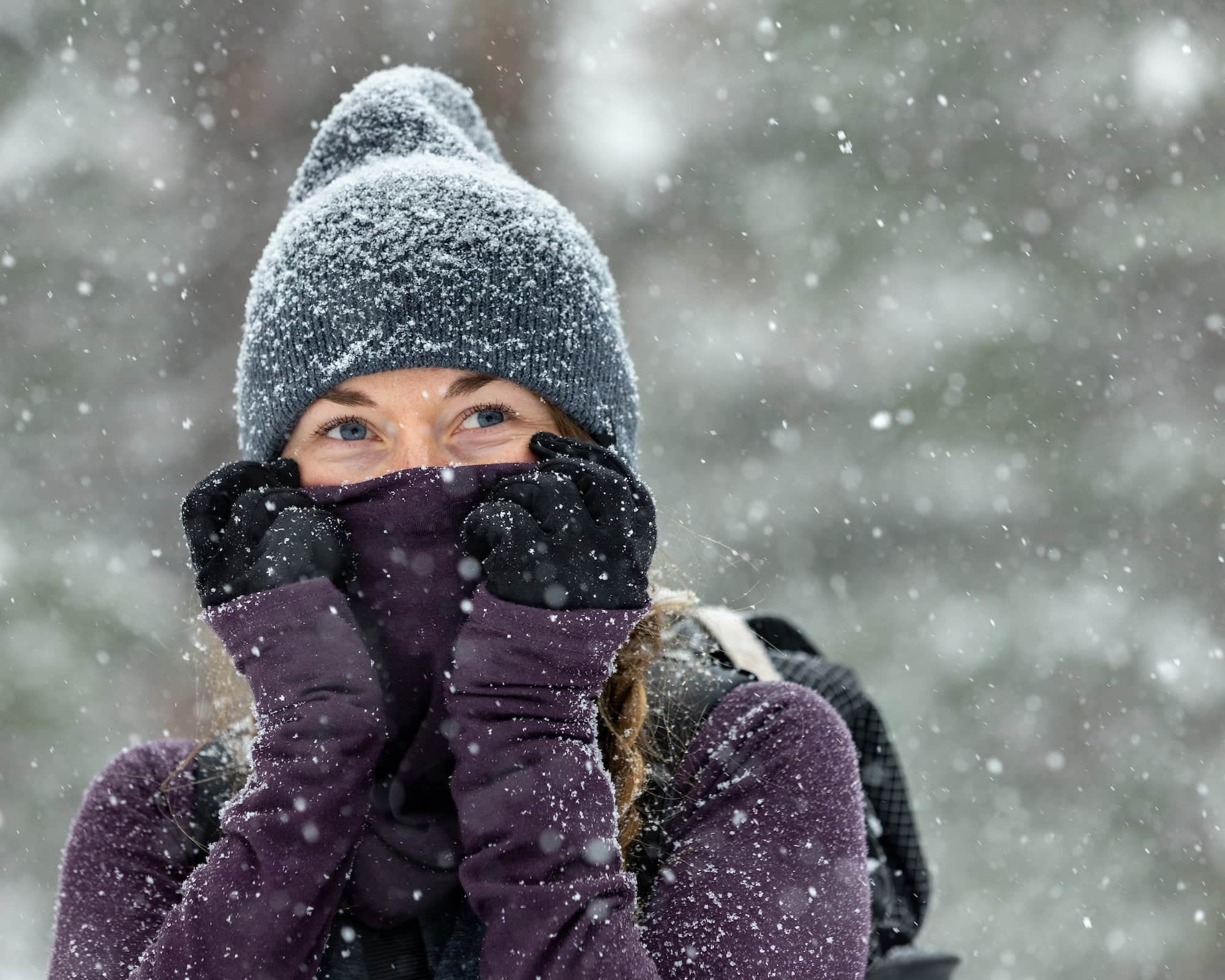 a woman wears a Ridge Merino beanie and Aspect High Neck Top in the snow