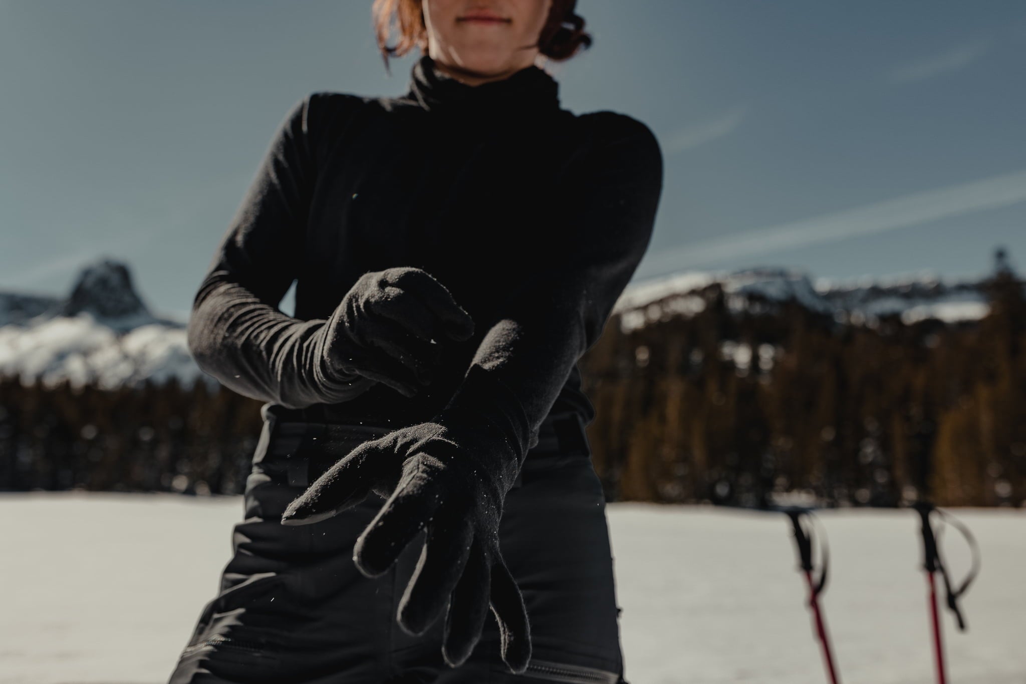 a woman puts on glove liners in the Mammoth Lakes Basin while backcountry skiing