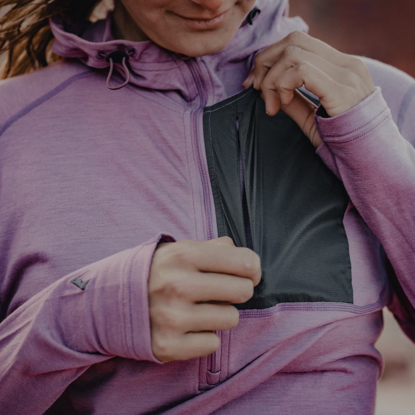 a woman shows the lightweight chest pocket on the Ridge Solstice Pro Sun Hoodie