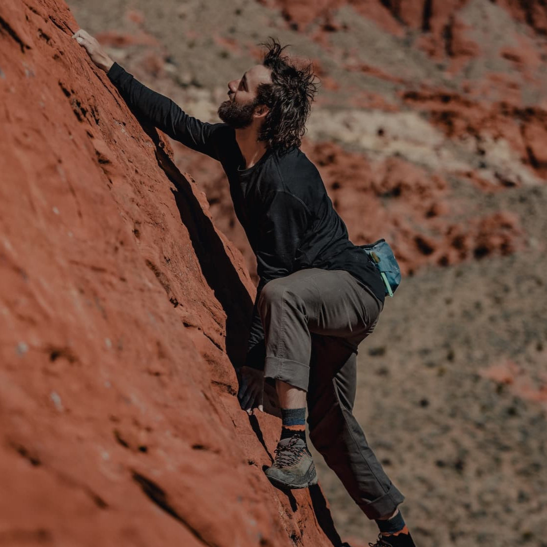 a man casually bouldering in a black Pursuit long sleeve tee