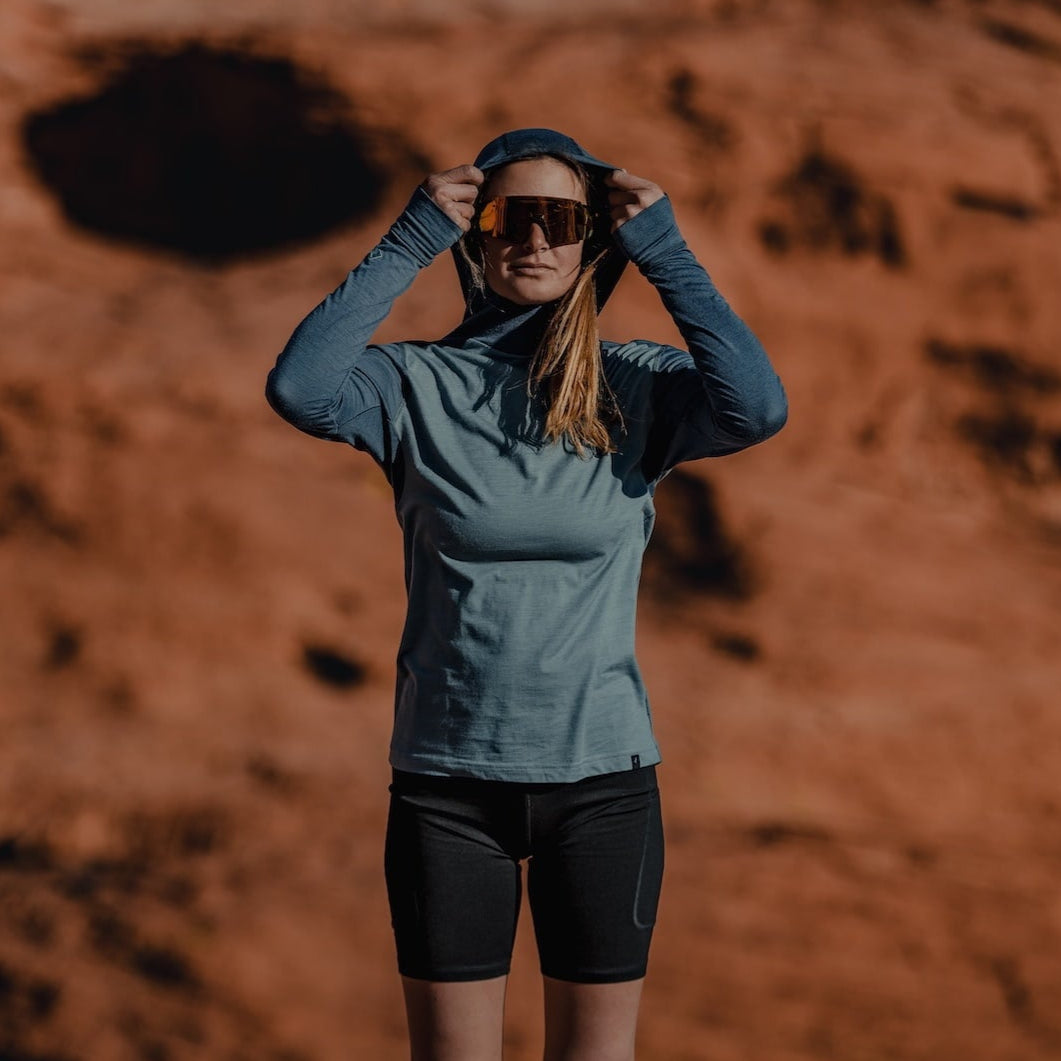 A woman wearing a Pursuit Hoodie in the desert