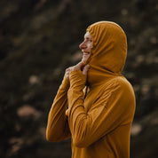 a man smiles wearing the Solstice Hoodie with the hood up