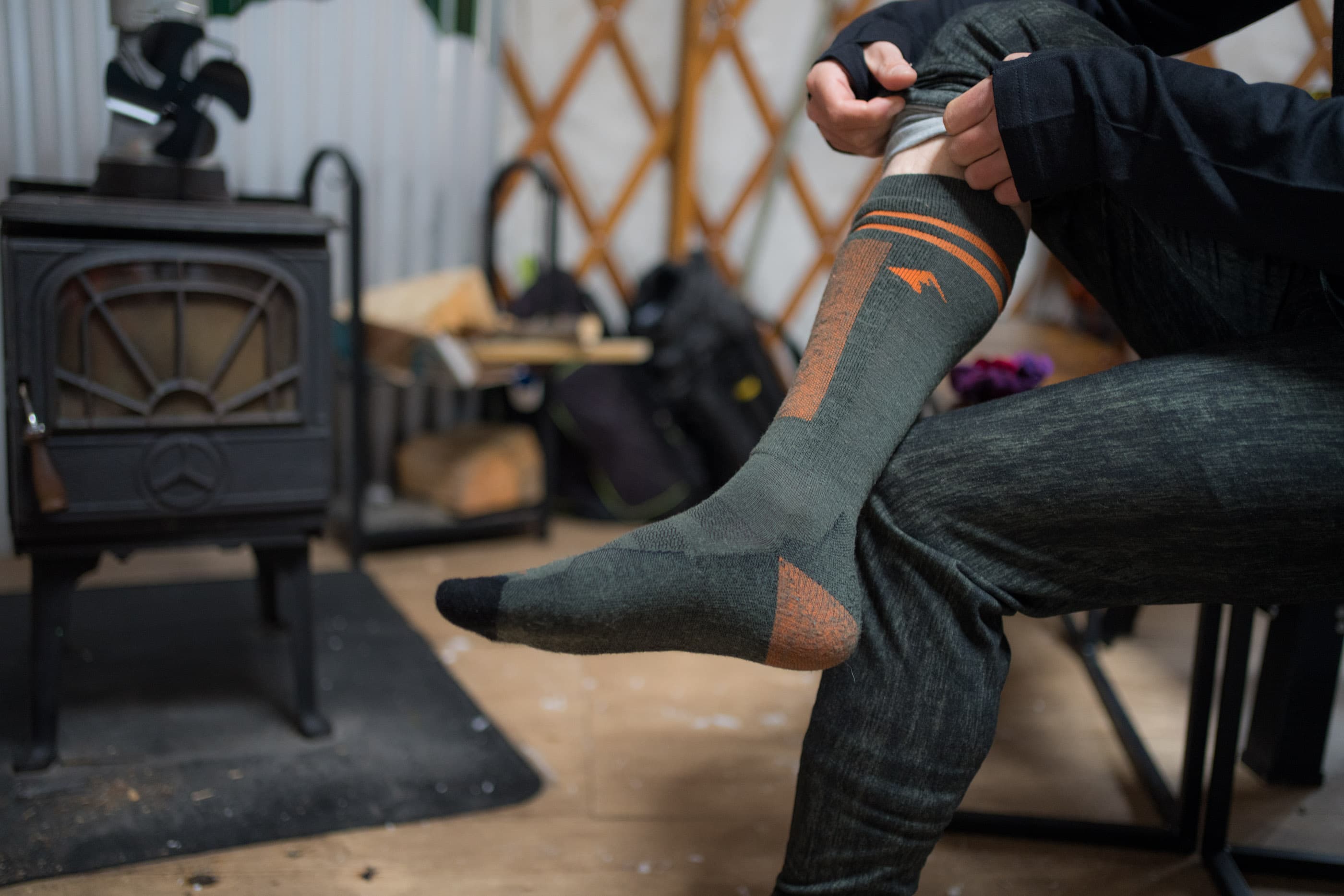 a man putting on ski socks in a backcountry yurt